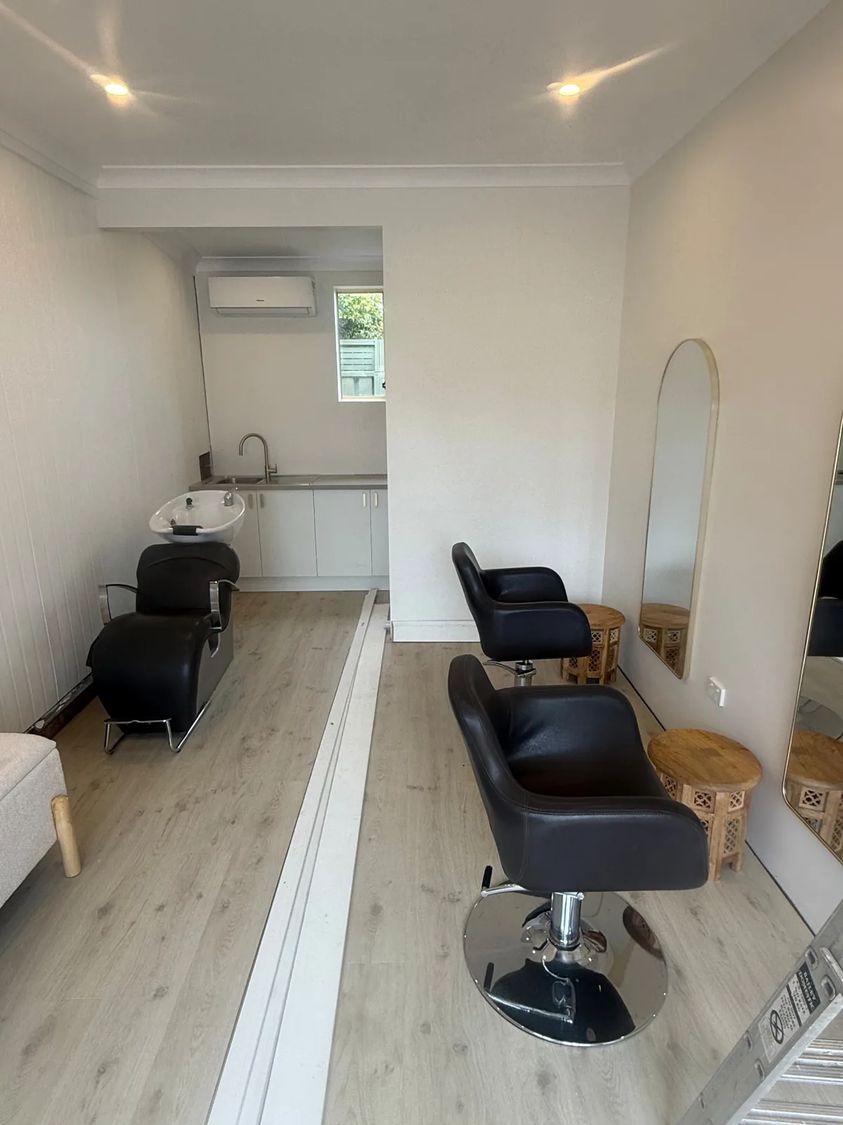 Salon chairs, wall mirrors and a basin at the rear of the room