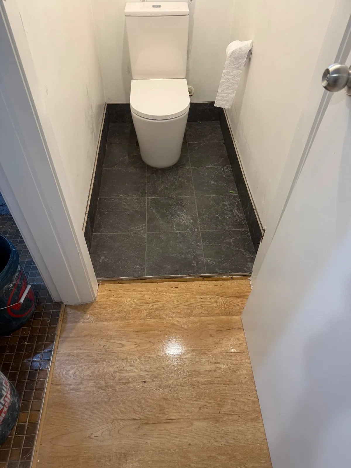 White toilet in a narrow room with grey floor tiles