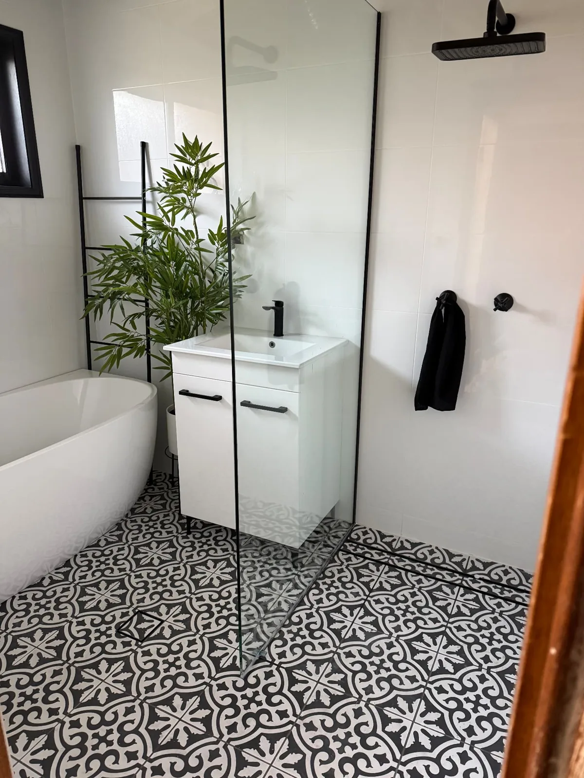 White freestanding bath, black shower fittings and patterned floor tiles