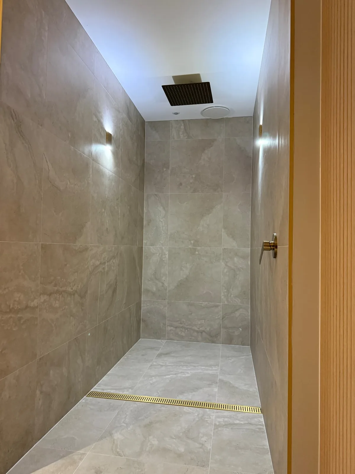 Light tiled shower with a recessed shelf and ceiling skylight